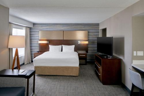 a hotel room with a bed and a flat screen tv at Residence Inn by Marriott Rochester West Greece in Rochester