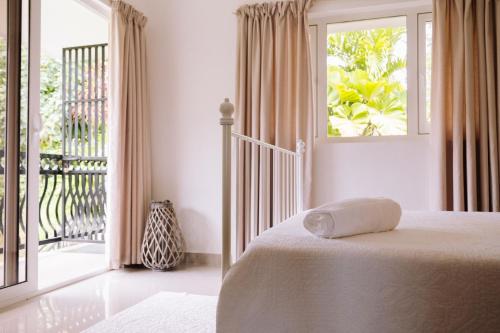 a white bedroom with a bed and a balcony at SOUTH HILL VILLA in Mahe