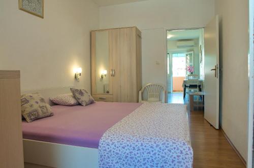 a bedroom with a large bed with purple sheets at Apartment Ella in Trogir