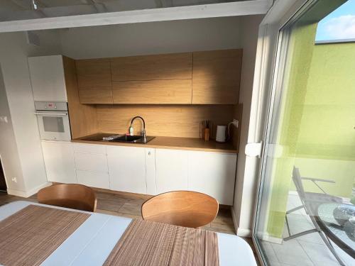 a kitchen with white cabinets and a sink at Apartamenty Pod Żaglami in Dziwnówek
