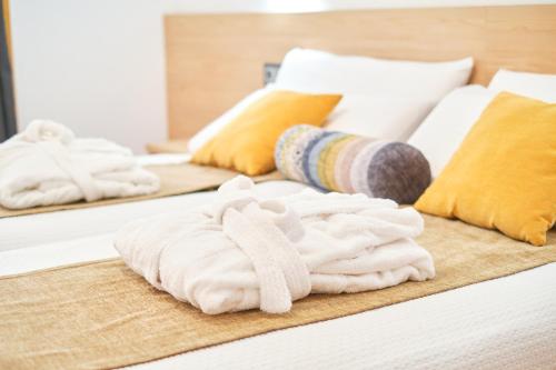 dos toallas blancas están sentadas en una cama en Hotel Don Manuel, en Gijón