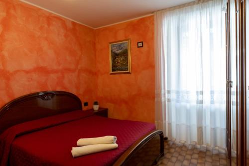 a bedroom with a red bed with two towels on it at Albergo San Michele in Tirano