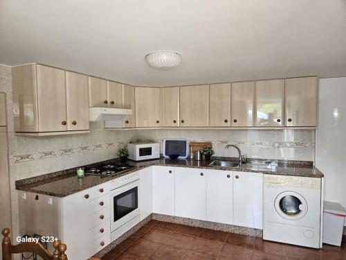 a kitchen with white cabinets and a sink and a dishwasher at Casa Lina VUT OR 000784 in Allariz