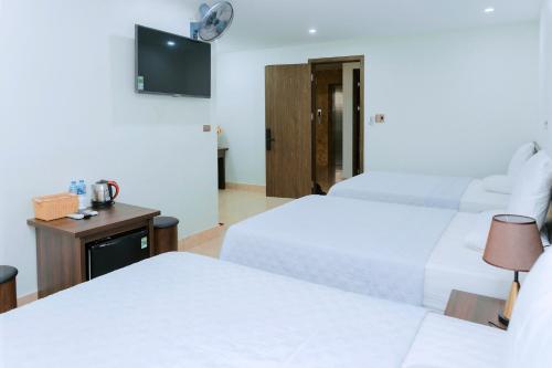 a hotel room with two beds and a tv at Thu Ha Hotel in Uông Bí