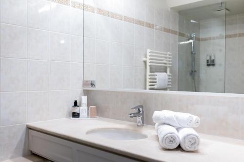 a bathroom with a sink and a mirror and towels at Le Relais Saint Michel in Le Mont Saint Michel