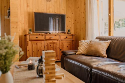 a living room with a couch and a television on a wooden cabinet at Chata MINERAL in Kováčová