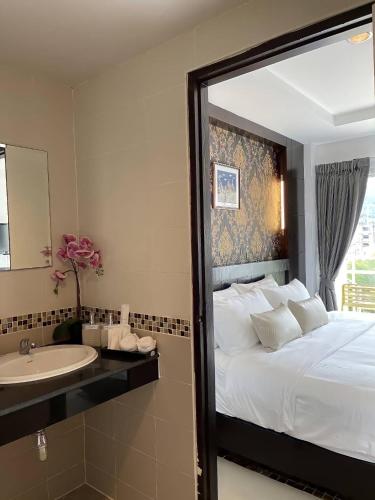 a bedroom with a bed and a sink and a mirror at Elephant Room in Patong Beach