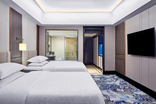 a hotel room with two beds and a flat screen tv at Sheraton Surabaya Hotel & Towers in Surabaya