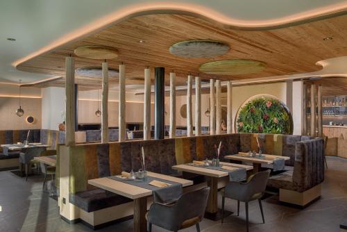 restauracja z drewnianymi sufitami, stołami i krzesłami w obiekcie Martinshof berg herz hotel w mieście San Giovanni in Val Aurina
