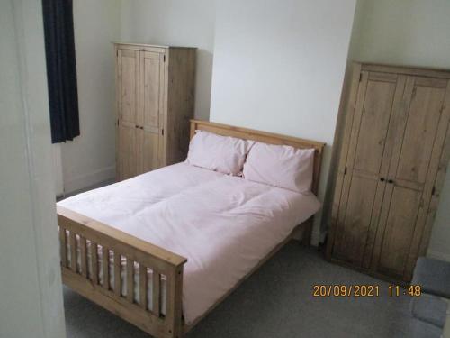 a bed with white sheets and two wooden cabinets at Cheerful well presented 3 Bedroom period house in Forest Hill