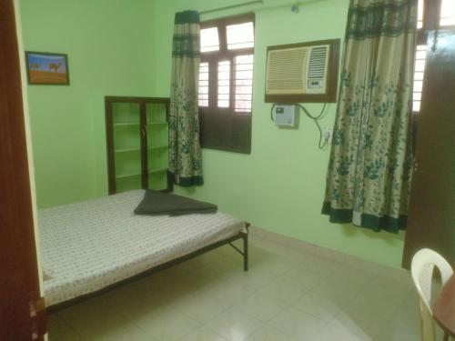 um pequeno quarto com uma cama e uma janela em Cherry Blossom em Pondicherry