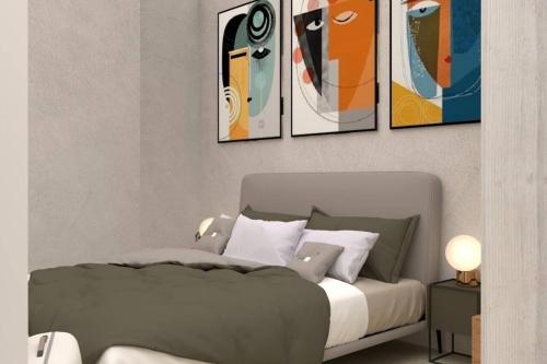 a bedroom with a bed with four paintings on the wall at David Design Apartment centro storico in Caorle
