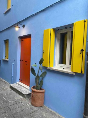 a blue building with yellow windows and a potted plant at David Design Apartment centro storico in Caorle
