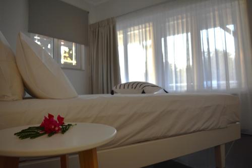 Un dormitorio con una cama blanca y una mesa con una flor. en Tarmaros Apartments, en Sissi