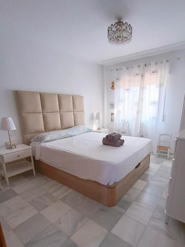 a white bedroom with a large bed and a chandelier at Casa Beatriz in Rincón de la Victoria