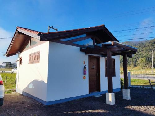 un pequeño edificio blanco con techo marrón en Pousada Estrela Do Luar, en Urubici