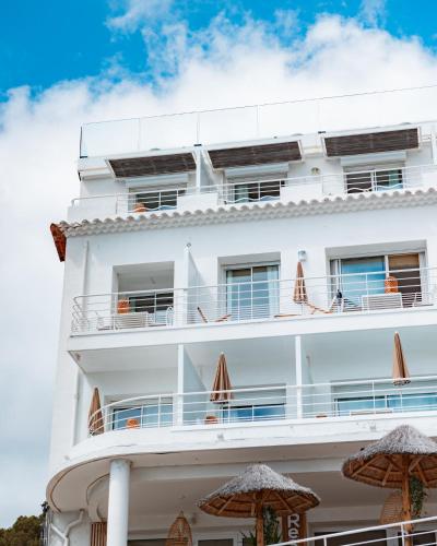 a white building with umbrellas in front of it at Hotel de La Plage - Mahogany in Cassis
