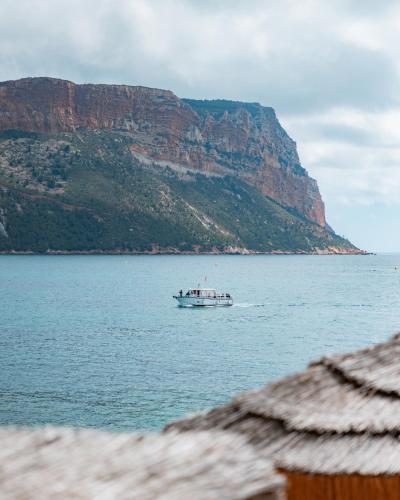 a boat on the water in front of a mountain at Hotel de La Plage - Mahogany in Cassis