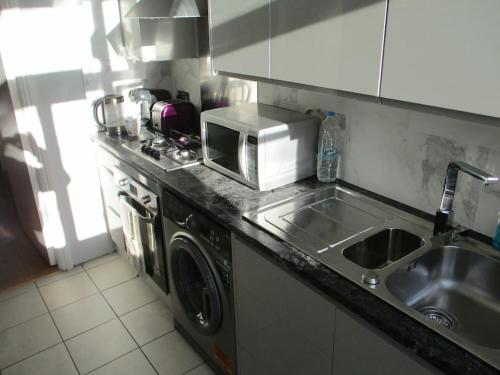 a kitchen counter with a sink and a microwave at Cheerful well presented 3 Bedroom period house in Forest Hill