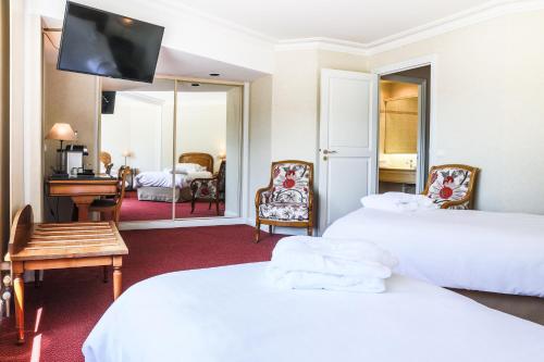 a hotel room with two beds and a flat screen tv at Le Relais Saint Michel in Le Mont Saint Michel