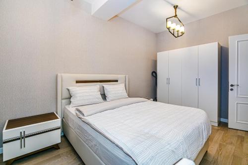 a bedroom with a white bed and a white cabinet at Sabah residance one bedroom in Baku