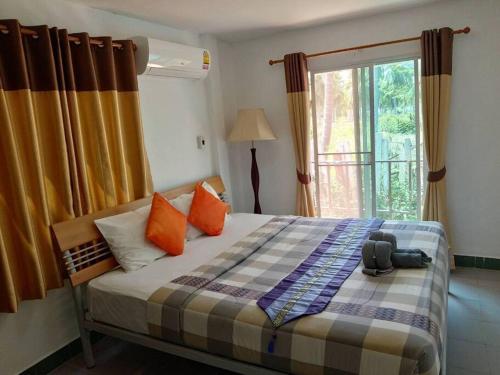 2-bed house near beach w/ aircon في بان كروت: غرفة نوم مع سرير مع وسائد برتقالية ونافذة