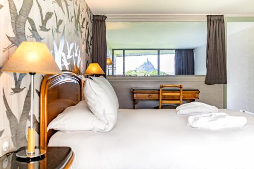 a hotel room with two beds and a desk at Le Relais Saint Michel in Le Mont Saint Michel