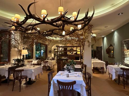 een restaurant met witte tafels en een grote kroonluchter bij Hotel Ristorante San Giuseppe in Cernobbio