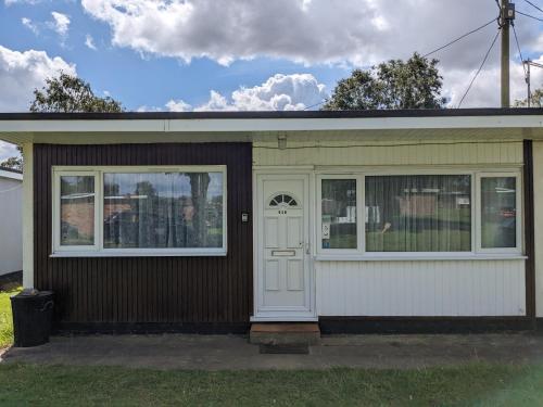 a small house with a white door and windows at Holiday at Hemsby in Hemsby
