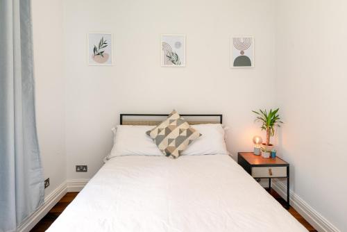 een slaapkamer met een bed met witte lakens en een tafel bij 2-Bedroom Victorian Apartment in Kensington in Londen