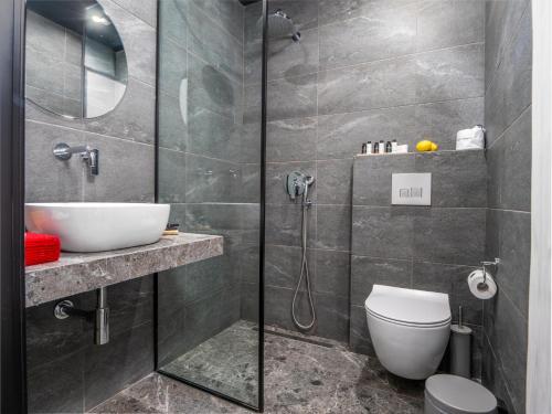 a bathroom with a shower and a toilet and a sink at Kalypso Suites Hotel - Adults Only in Elounda
