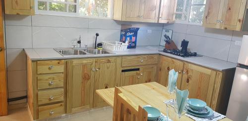 cocina con armarios de madera, fregadero y mesa en Private and quiet room, en Jarabacoa