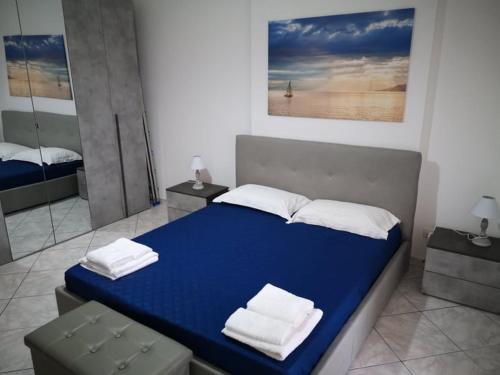 una camera da letto con un letto blu e asciugamani di The Sail Apartment - Marzamemi a Marzamemi