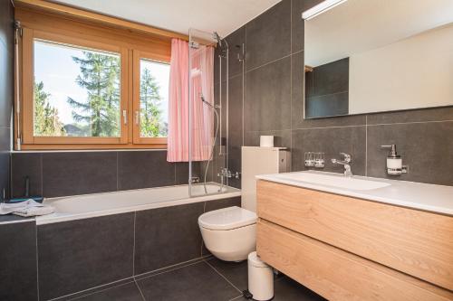 uma casa de banho com um WC e uma janela. em Ferienhaus Felicé em Zermatt