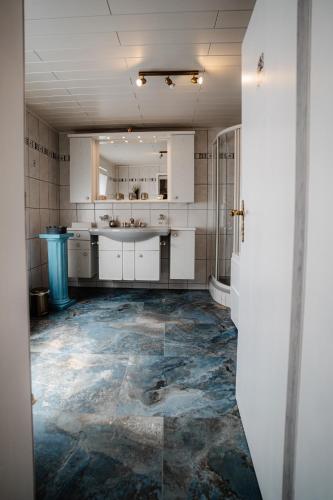 a kitchen with white cabinets and a blue floor at Timeout Royal in Ellar