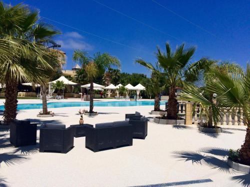 einen Pool mit Stühlen und Palmen in einem Resort in der Unterkunft Grand Hotel Stella Maris Italia in Palmi