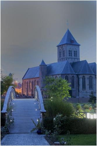 a church with a bridge in front of a building at B&B De Rentmeesterhoeve in Reningelst