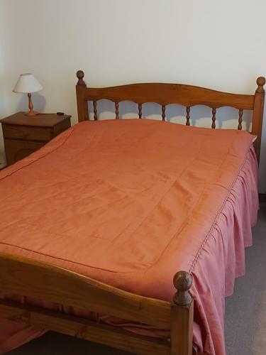 una cama de madera con una manta naranja encima en GRAN MAR 2 AMBIENTES en Necochea