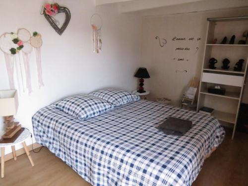 ein Schlafzimmer mit einem Bett mit einer blau-weißen karierten Decke in der Unterkunft chambre d’hôte naturiste ou pas in Miniac-Morvan