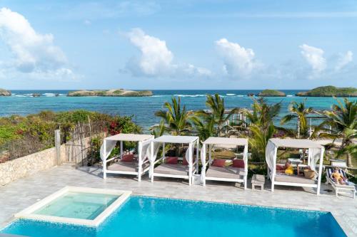 a pool with chairs and the ocean in the background at Visiwa Beach Resort in Watamu