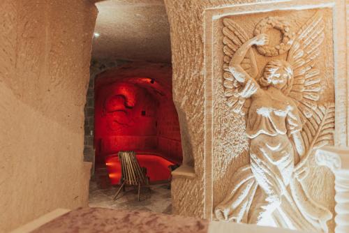 een kamer met een rode bank en een standbeeld van een engel bij Harem Suites Cappadocia in Uchisar