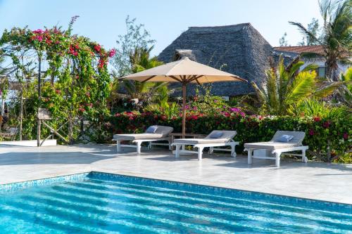 a swimming pool with two chairs and an umbrella next to a pool at Visiwa Beach Resort in Watamu