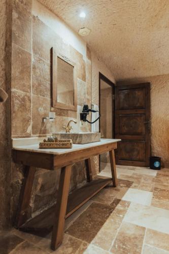 a bathroom with a sink and a wooden table at Harem Suites Cappadocia in Uchisar