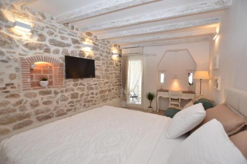 ロヴィニにあるApartment Al Pozzoの白いベッドと石の壁が備わるベッドルーム1室
