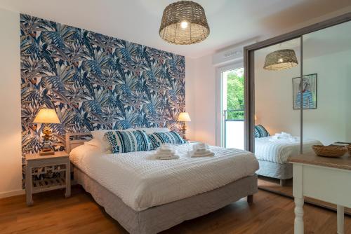 1 dormitorio con 1 cama grande y papel pintado de flores azul en Îlots Dido - Appt proche de la mer, en Concarneau