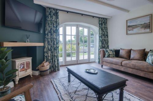 a living room with a couch and a table at The Stables - 2 Bedroom Cottage - Princes Gate in Ludchurch