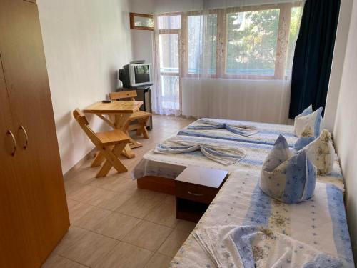 a room with two beds and a table and a microwave at Къща за гости Уют in Sveti Vlas