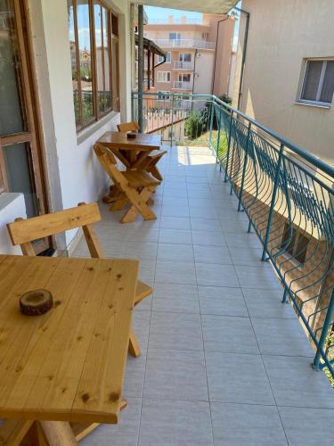 a balcony with wooden tables and benches on a building at Къща за гости Уют in Sveti Vlas