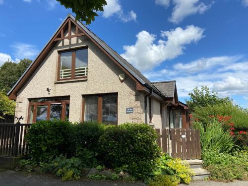 a house with a fence in front of it at The Lodge at Woodend in Kemnay