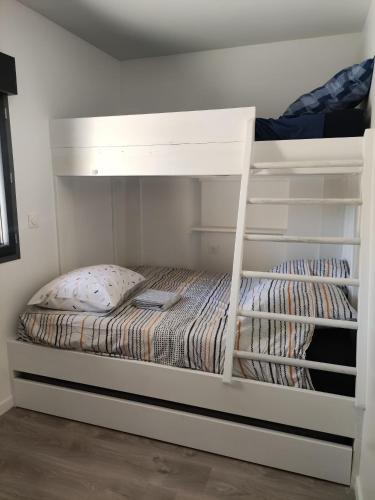 Ce lit superposé blanc se trouve dans un dortoir. dans l'établissement La maison du Moulin près Lascaux, à Auriac-du-Périgord
